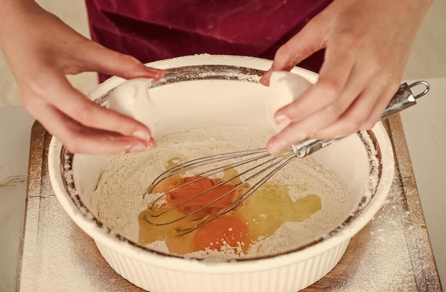 Zdjęcie dziewczynka ubijająca jajko i mąkę do robienia ciasta z gotowaniem na trzepaczce