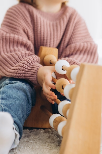 Dziewczynka uczy się kolorów bawiąc się drewnianymi cylindrycznymi zabawkami z kolorowymi postaciami ludzi i umieszczając je w kubeczkach w odpowiednim kolorze Dziecko jest szczęśliwe, że poprawnie wykonało zadanie