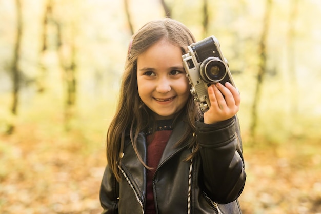 Dziewczynka używająca staromodnego aparatu w jesiennym fotografie przyrody w sezonie jesiennym i koncepcji wypoczynku