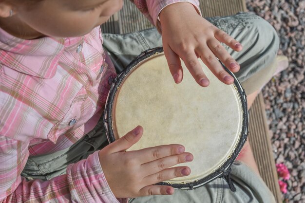 Dziewczynka z bębenkiem djembe na zewnątrz na werandzie domu zdjęcie bez obróbki