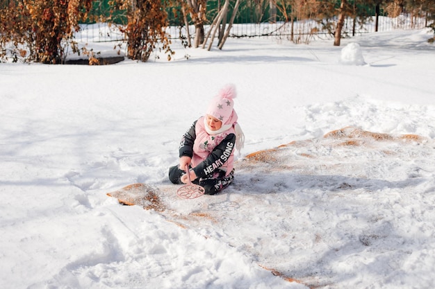 Dziewczynka zimą siedzi na dywanie dziecko uczy się czyścić dywan tradycyjną metodą za pomocą ...