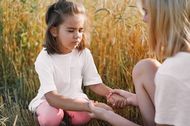 Zdjęcie dziewczyny, modląc się i trzymając się za ręce w polu pszenicy. módlcie się o wzajemne wsparcie boga.