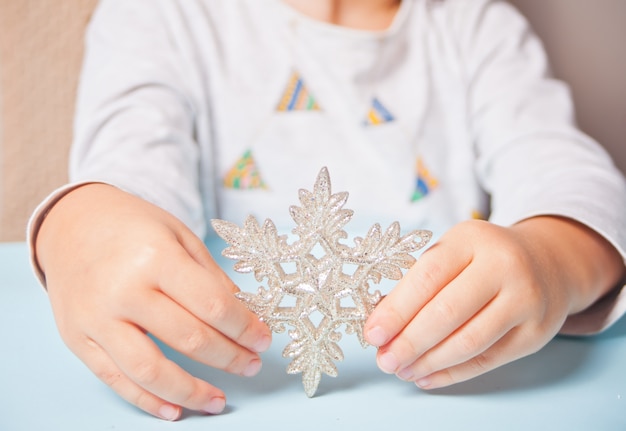 Zdjęcie dziewczyny ręka trzyma boże narodzenie wystroju dużego płatka śniegu w rękach na błękicie