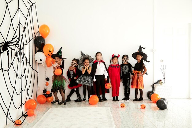 Zdjęcie dziewczyny w różnych kostiumach stojące na ścianie podczas halloween