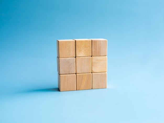 Dziewięć pustych prostych drewnianych puzzli układających się w stosy układających się na białym tle na niebieskim tle minimalistycznym stylu Rozwiązanie rozwiązuje problem koncepcje celu biznesowego i planu sukcesu