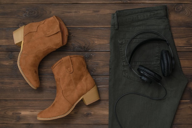 Dżinsy, buty i słuchawki na drewnianym tle. Pojęcie muzyki ludowej.