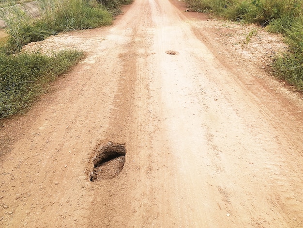 Zdjęcie dziura na zakurzonej glebowej drodze w wsi