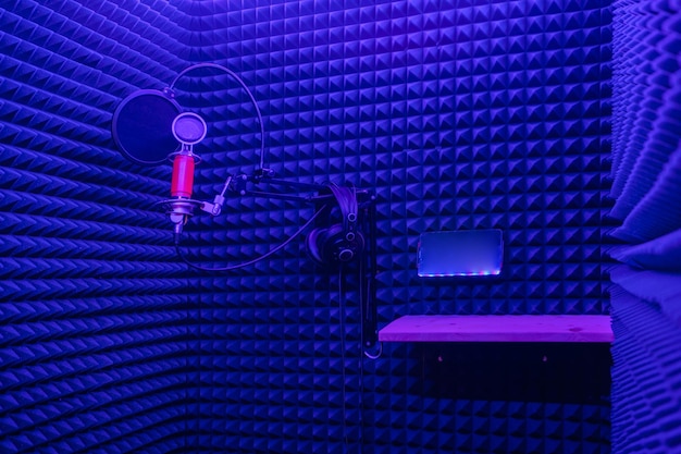 Zdjęcie dźwiękoszczelny pokój studyjny do nagrywania piosenek z mikrofonami w ciemnoniebieskim świetle neonowym