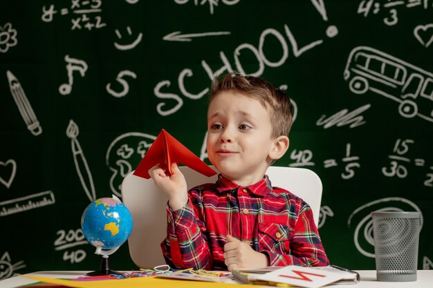 Edukacja Domowa Lub Szkolna. Uczeń Z Papierowym Samolotem. Portret Dziecka Ze Szkoły Podstawowej.