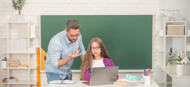 Edukacja Dziecięca. Skoncentrowany Uczeń I Nauczyciel Z Laptopem. Ojciec I Nastolatka Studiują.