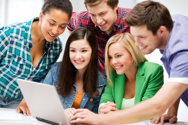 edukacja i internet - uśmiechnięci uczniowie patrzący na tablet podczas wykładu w szkole