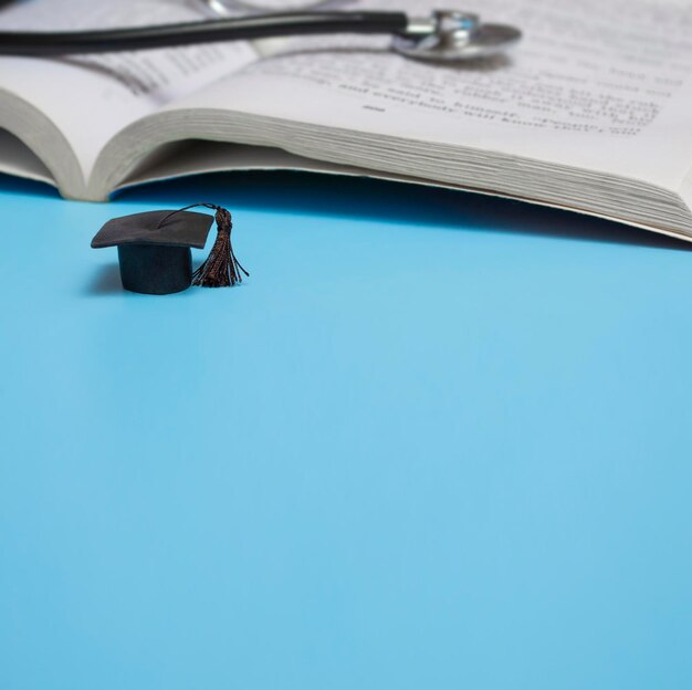 Zdjęcie edukacja medyczna stetoskop książka i kapelusz absolwent koncepcja medyczna na niebieskim tle absolwent baner