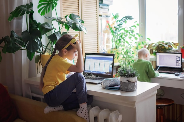 Edukacja na odległość w domu dwoje rodzeństwa odrabiające razem pracę domową w jednym pokoju zamknięcie nowa norma