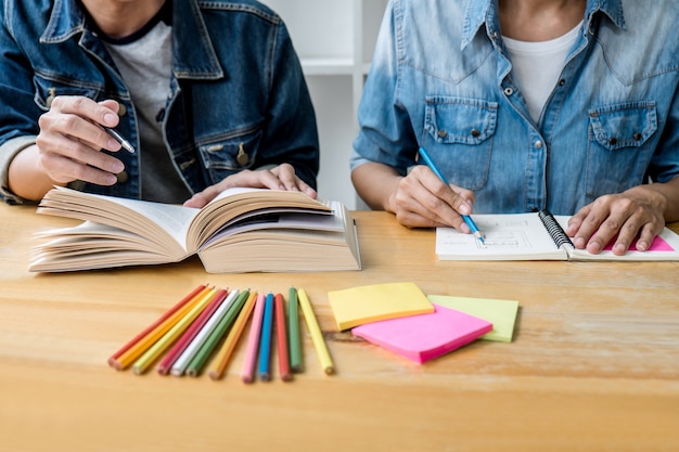 Edukacja, nauczanie, uczenie się, technologia i koncepcja ludzi. Dwaj uczniowie szkół średnich lub koledzy z klasy pomagają przyjacielowi w odrabianiu lekcji w klasie, książki nauczyciela z przyjaciółmi