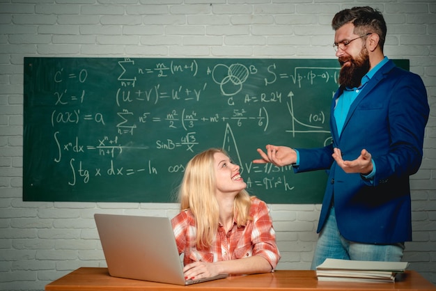 Edukacja Nauczyciel pomagający młodemu uczniowi w lekcji Korepetycje Uczeń i nauczyciel siedzący przy ławkach w klasie Seminarium uniwersyteckie Gotowi do szkoły Uczniowie przygotowujący się do egzaminów uniwersyteckich