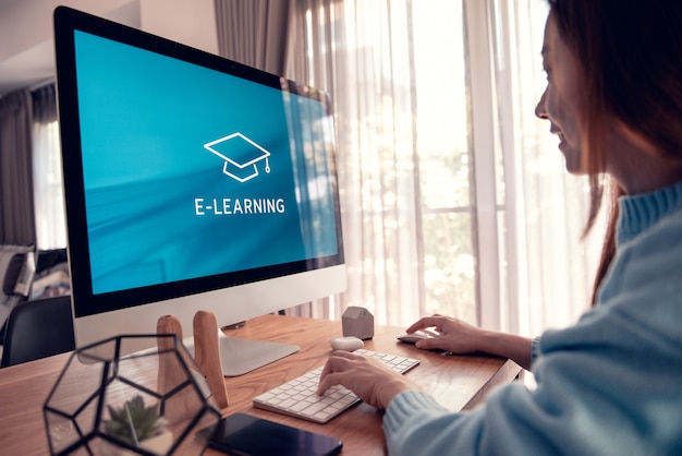 Edukacja Online, E-learning. Młoda Kobieta Siedzi Przy Stole, Pracując Na Monitorze Komputera Z Napisem Na Ekranie