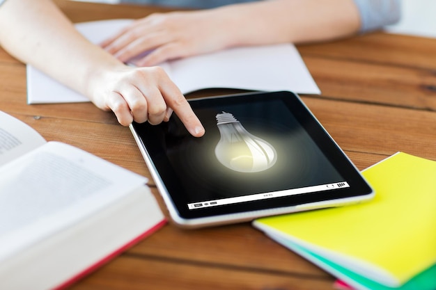 edukacja, pomysł, technologia i koncepcja internetu - zbliżenie studentki z żarówką na komputerze typu tablet pc i notebooku w domu