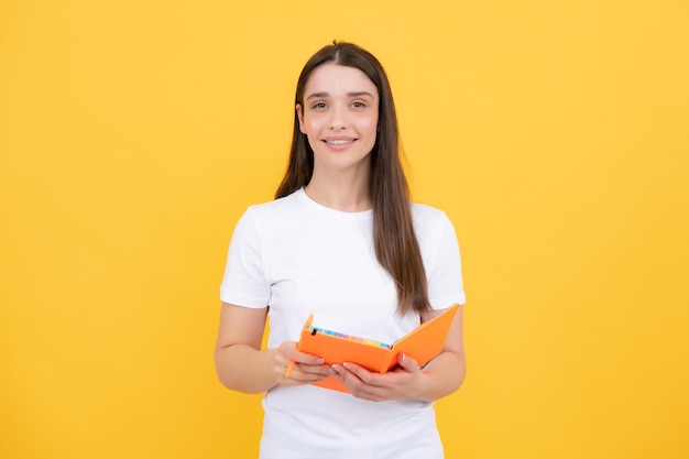 Edukacja studencka w szkole średniej koncepcja college'u Szczęśliwa młoda dziewczyna trzyma notatnik Inteligentnie wyglądający studentka na żółtym tle