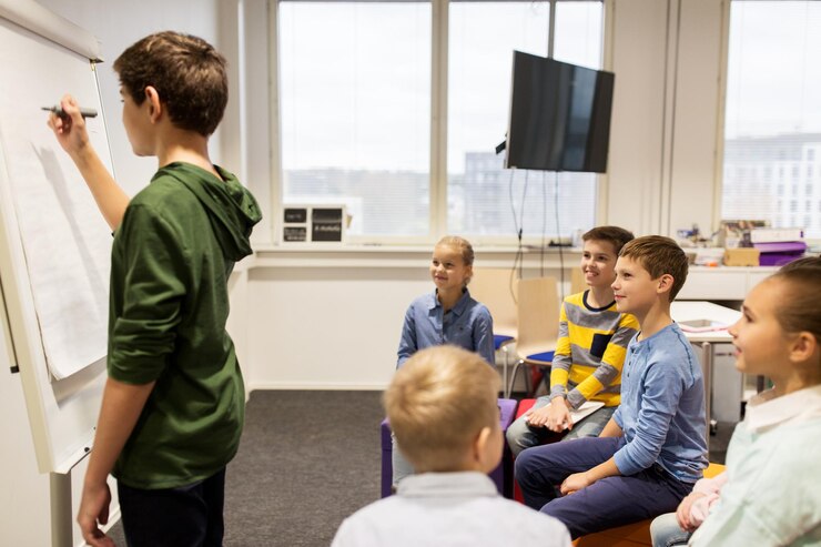 Zdjęcie edukacja, szkoła podstawowa, nauka i koncepcja ludzi - szczęśliwy uczeń chłopiec z markerem piszącym na klapce