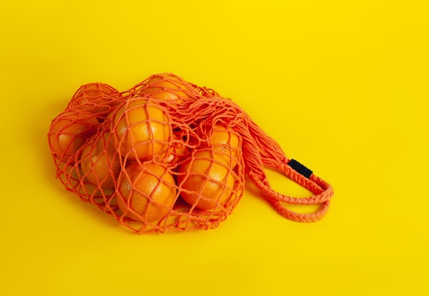 Eko torba z pomarańczami na kolorowym tle. koncepcja recyklingu