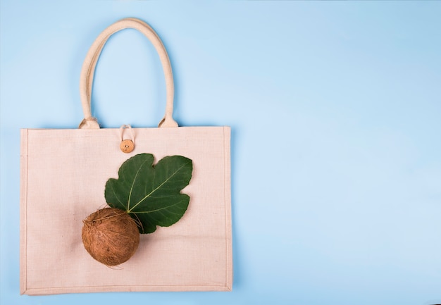 Ekologiczna bawełniana torba z kokosem i liściem figi na pastelowym niebieskim, copyspace, minimalistycznym stylu