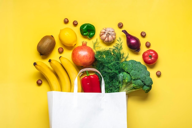 Zdjęcie ekologiczna papierowa torba sklepowa z surowymi organicznymi zielonymi warzywami wyizolowanymi na żółtym tle płaski widok z góry koncepcja zero odpadów z tworzyw sztucznych zdrowa, czysta dieta i koncepcja rolnictwa detoksykacji