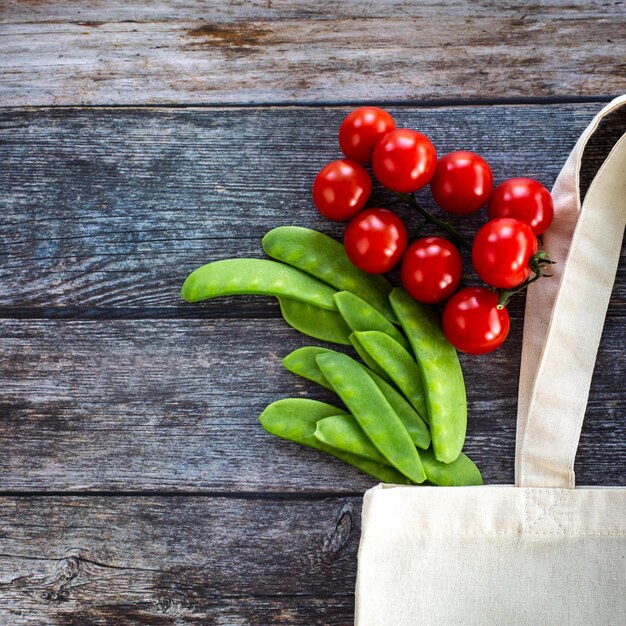 Ekologiczna torba na zakupy ze świeżymi organicznymi warzywami i sałatką na drewnianym tle Flat Lay