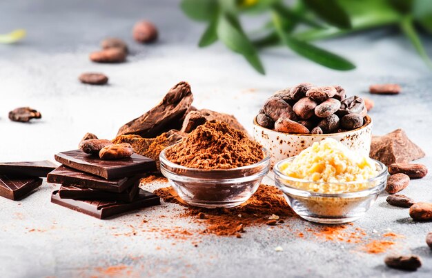 Ekologiczne masło kakaowe ziarna kakaowe tarte grudki kakaowe ciemna czekolada na szarym tle