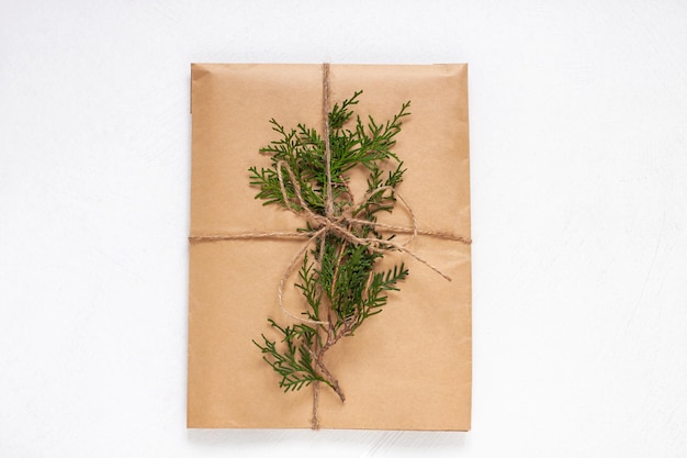 Ekologiczne pudełko upominkowe pakowane w papier pakowy na białym tle izolowane Vintage ekologiczny styl naturalny Kompozycja z prezentem ozdobionym gałązkami choinki Widok z góryMakieta płaska noworocznego