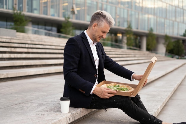 Ekonomista robi sobie przerwę na lunch jest pizza Mężczyzna jest siwowłosym finansistą