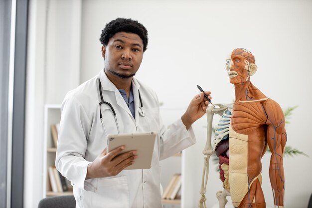 Ekspert badający kość ramienną za pomocą tabletu i modelu w miejscu pracy