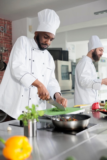 Ekspert gastronomiczny w profesjonalnej kuchni restauracyjnej, siekający świeże warzywa podczas gotowania wykwintnego dania na obiad. Szef kuchni przygotowuje składniki i przyprawy do gulaszu warzywnego.