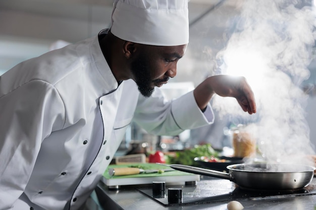 Ekspert kulinarny przygotowujący serwis obiadowy z wykorzystaniem świeżych warzyw i ziół w profesjonalnej kuchni restauracji. Wykwalifikowany ekspert gastronomii przyprawiający jedzenie parmezanem.