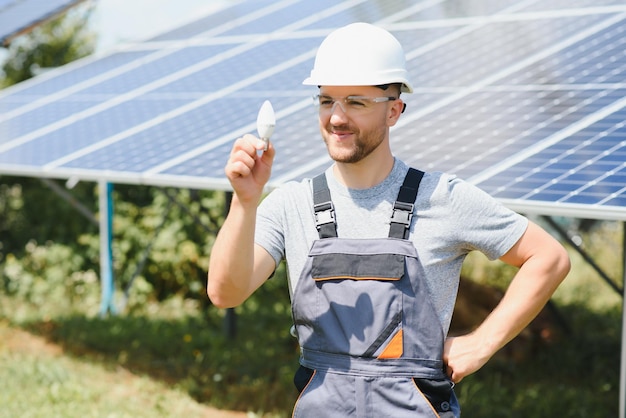 Ekspert techniczny w panelach fotowoltaicznych, pilot wykonuje rutynowe czynności monitorowania systemu wykorzystując czystą energię odnawialną w dłoni żarówkę.