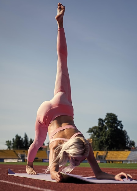 Elastyczna kobieta rozciągająca się na stadionie w sportowej pilates