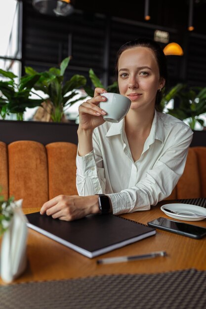 elegancka bizneswoman mająca przerwę na kawę siedząc w restauracji z filiżanką