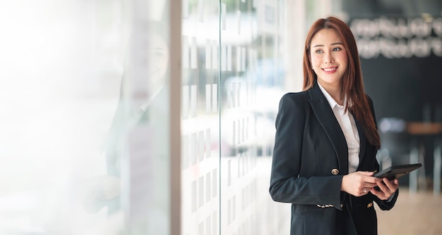 Elegancka bizneswoman pozycja w biurze z cyfrową pastylką