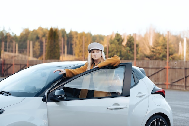 Elegancka bizneswoman w średnim wieku stojąca przy samochodzie jesień moda autentyczny portret