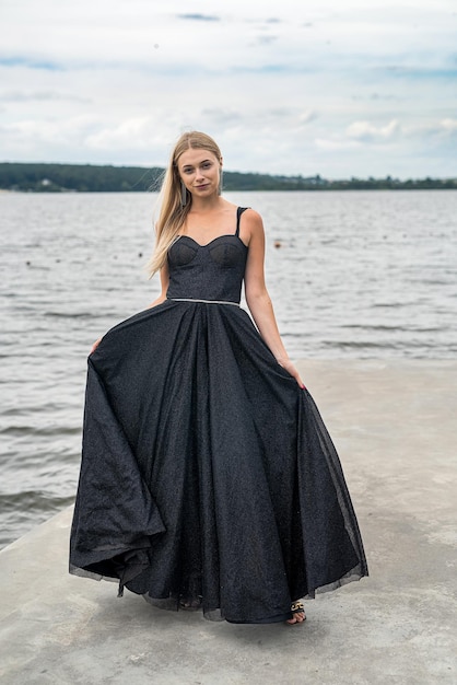 Elegancka blondynka w modnej czarnej sukience nocnej w pobliżu jeziora