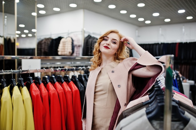 Elegancka blondynka w płaszczu w sklepie futra i kurtki skórzane.