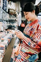 Zdjęcie elegancka japońska żona zakupy w sklepie sprzedającym skarpetki, ręczniki i torby. młoda dziewczyna kupując wybierając w sklepie dla rodziny. piękna pani w kimono sukienka uśmiechający się gospodarstwa produktów czytanie etykiety odzieży.