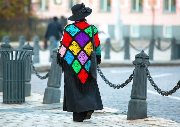Zdjęcie elegancka kobieta w kolorowym płaszczu spaceruje ulicą miasta