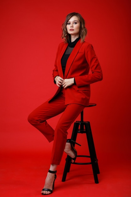 Elegancka młoda kobieta w czerwonym garniturze spodnie spodnie czarna bluzka na tle Monochrome