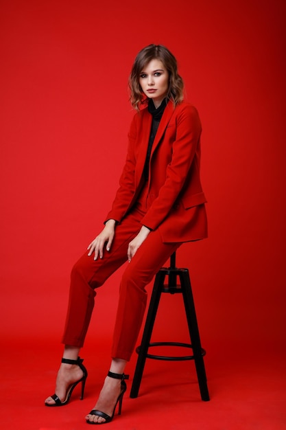 Elegancka młoda kobieta w czerwonym garniturze spodnie spodnie czarna bluzka na tle Monochrome