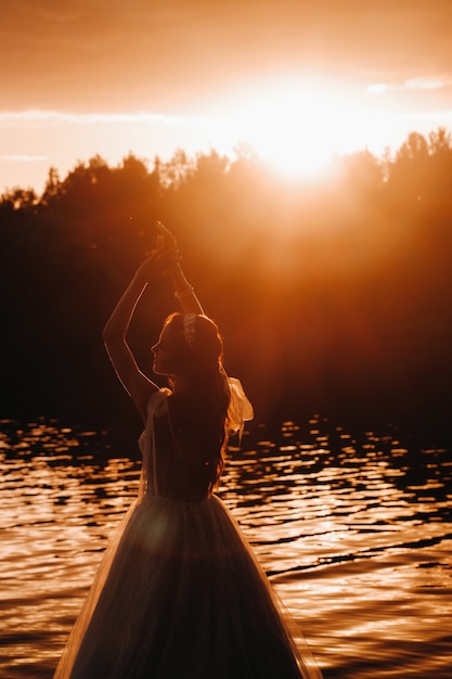 Elegancka panna młoda w białej sukni cieszy się naturą o zachodzie słońca.Model w sukni ślubnej w przyrodzie w Parku.Białoruś