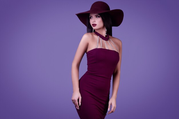 Elegancka piękna brunetka kobieta w fioletowej sukience i szerokim kapeluszu