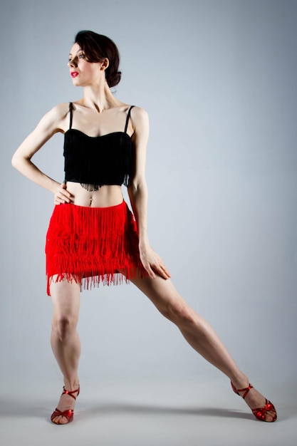 Elegancka tancerka wykonuje taniec latynoamerykański w eleganckiej czerwonej sukience z biżuterią musującą Moda i uroda Pokaz baletowy Portret studyjny