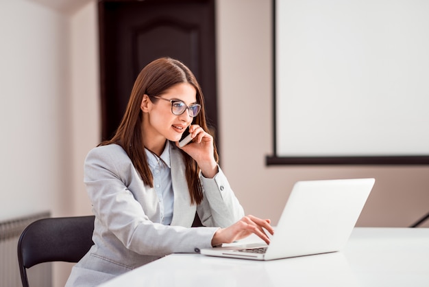 Elegancki Bizneswoman Opowiada Na Mądrze Telefonie I Pracuje Na Laptopie W Sala Konferencyjnej.