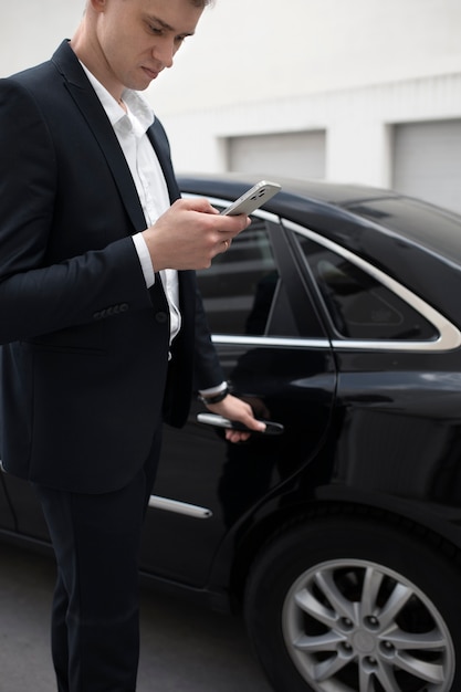 Elegancki mężczyzna stojący obok swojego samochodu w celu skorzystania z usług taksówek