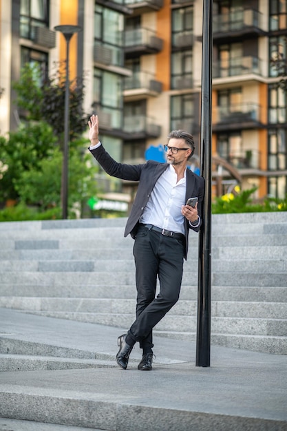 Elegancki mężczyzna w garniturze mężczyzna z telefonem w ręku na ulicy miasta